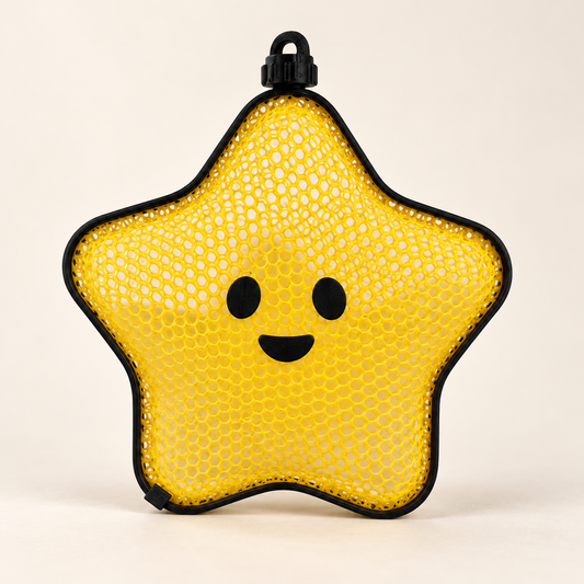 Styled studio mockup of a yellow mesh star ornament with black rim, smiling face and hanging loop